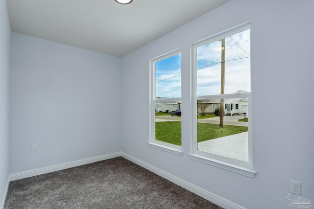 empty room featuring dark carpet and baseboards