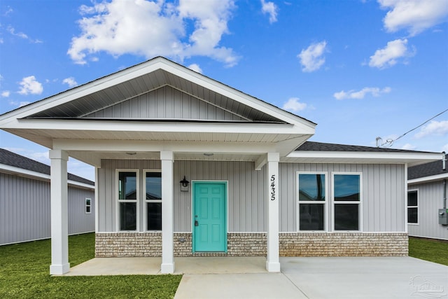 view of front of property featuring a porch, board and batten siding, and a front yard