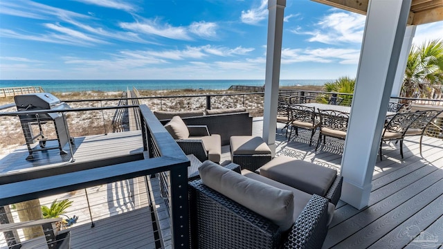 wooden terrace featuring outdoor lounge area, a water view, and a beach view