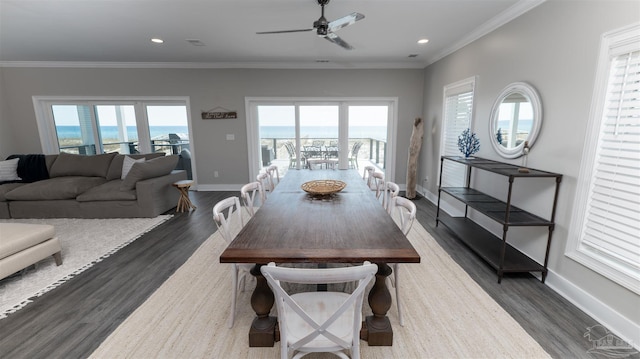 dining area with dark hardwood / wood-style flooring, a water view, and plenty of natural light