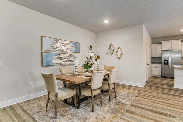 dining space featuring light wood-type flooring and a textured ceiling