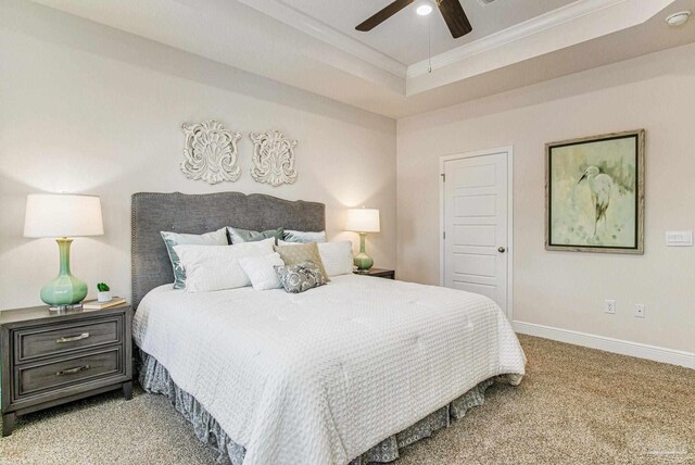 carpeted bedroom featuring ceiling fan, a raised ceiling, and ornamental molding