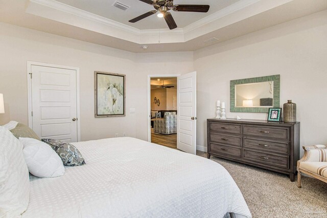 carpeted bedroom featuring a tray ceiling, ceiling fan, and crown molding