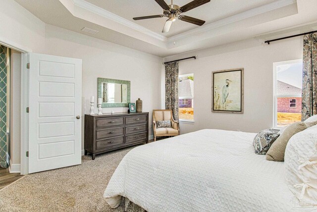 carpeted bedroom with ceiling fan, ornamental molding, and a tray ceiling