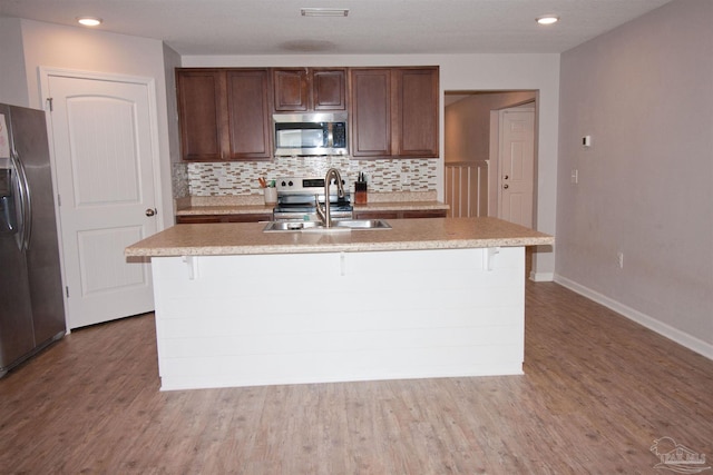 9453 Lutoo Ln, Pensacola, FL 32526 - kitchen with appliances with stainless steel finishes, a sink, decorative backsplash, wood finished floors, and a kitchen island with sink