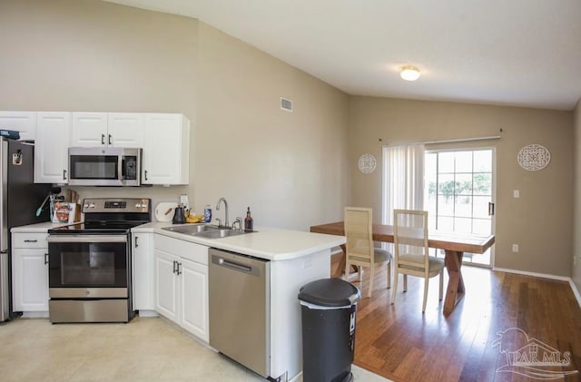 kitchen featuring light hardwood / wood-style flooring, kitchen peninsula, vaulted ceiling, stainless steel appliances, and sink