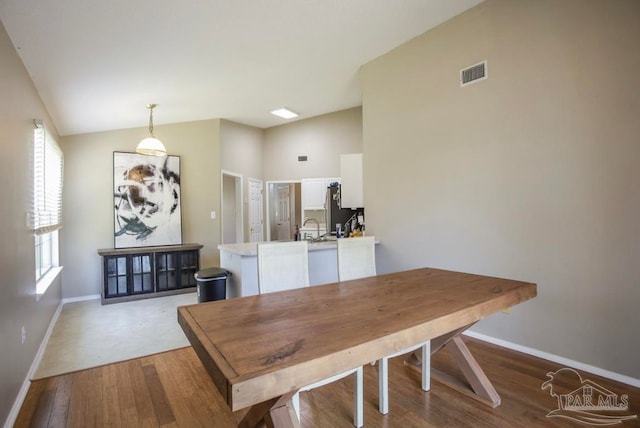 dining area featuring lofted ceiling, sink, and light hardwood / wood-style floors