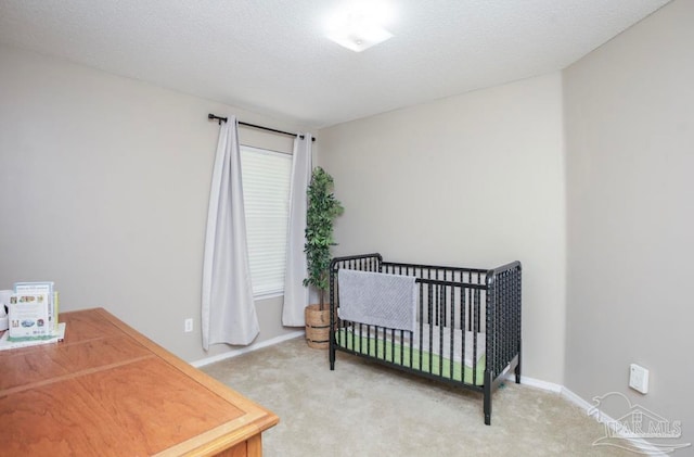 carpeted bedroom with a textured ceiling and a nursery area