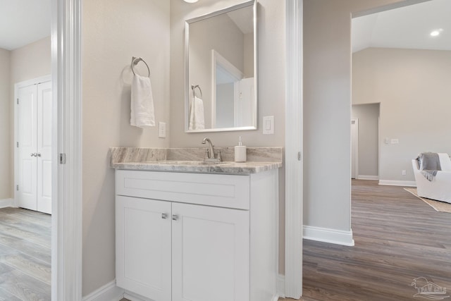 bathroom featuring vanity, hardwood / wood-style flooring, and vaulted ceiling