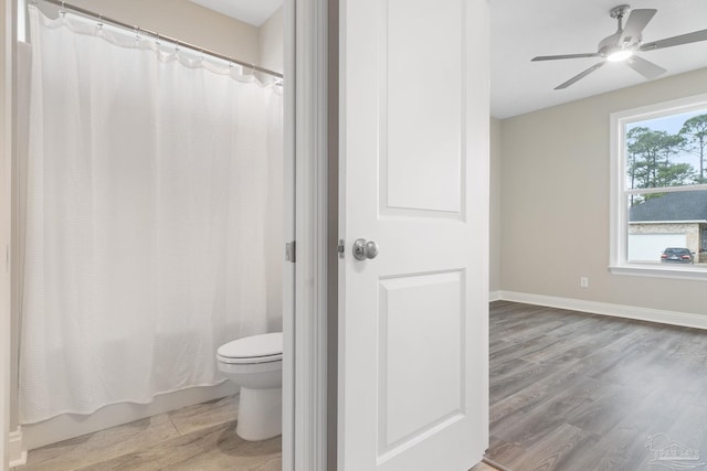 bathroom with hardwood / wood-style floors, shower / bath combination with curtain, toilet, and ceiling fan