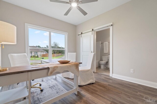 office area with dark wood-type flooring, a barn door, and ceiling fan