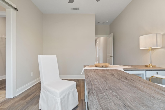 dining room with hardwood / wood-style floors, a barn door, and ceiling fan