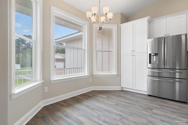 kitchen featuring a notable chandelier, stainless steel refrigerator with ice dispenser, pendant lighting, white cabinets, and light hardwood / wood-style flooring