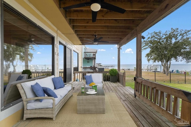 wooden terrace with a water view, outdoor lounge area, and ceiling fan