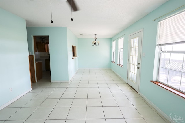 unfurnished room with ceiling fan with notable chandelier, light tile patterned flooring, and a textured ceiling