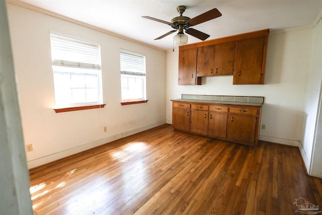 kitchen with hardwood / wood-style flooring, ceiling fan, and crown molding