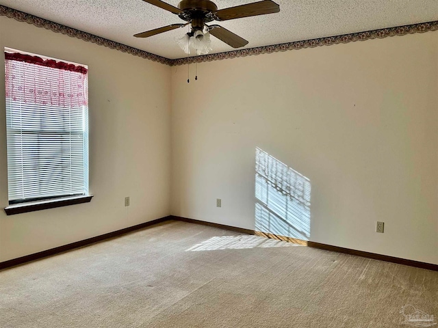 empty room featuring ceiling fan, light carpet, and a textured ceiling