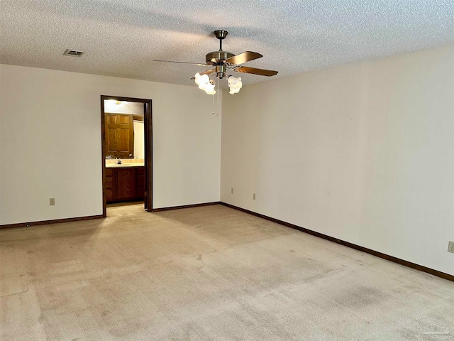 empty room featuring ceiling fan, light carpet, and a textured ceiling