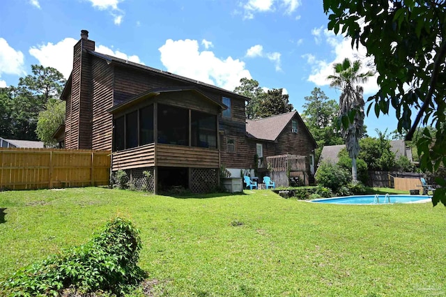 back of property featuring a fenced in pool, a yard, and a sunroom