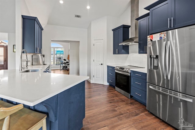 kitchen with wall chimney exhaust hood, a kitchen breakfast bar, tasteful backsplash, blue cabinets, and appliances with stainless steel finishes