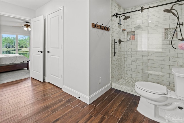 bathroom featuring ceiling fan, toilet, and a tile shower