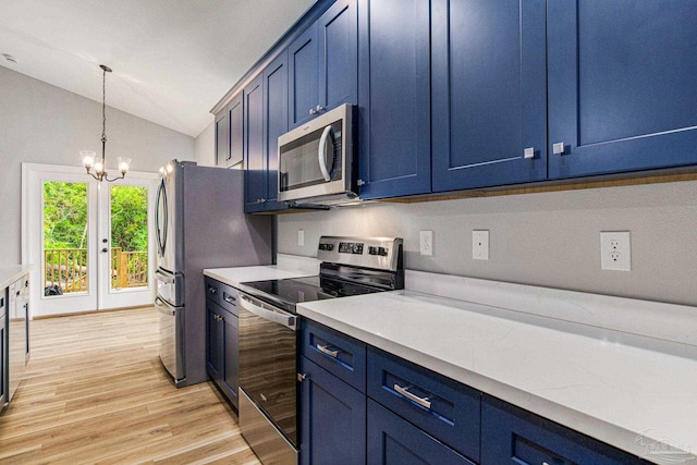 kitchen featuring a chandelier, hanging light fixtures, stainless steel appliances, vaulted ceiling, and light hardwood / wood-style flooring