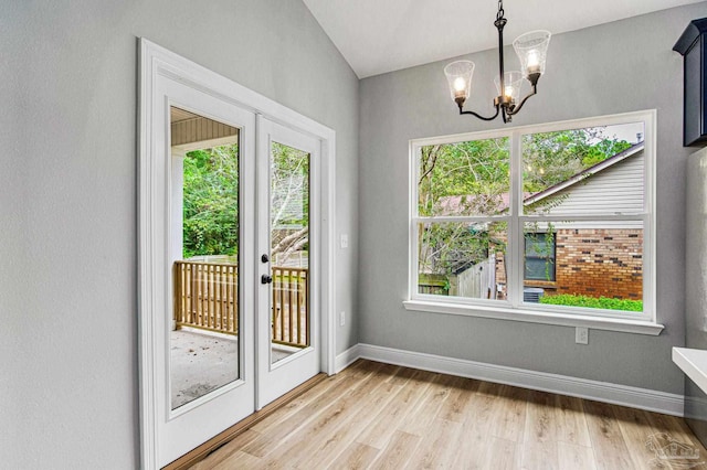 doorway to outside featuring a notable chandelier, a wealth of natural light, and light wood-type flooring