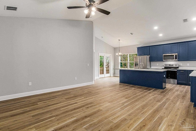 kitchen with ceiling fan with notable chandelier, high vaulted ceiling, appliances with stainless steel finishes, light hardwood / wood-style flooring, and a kitchen island with sink