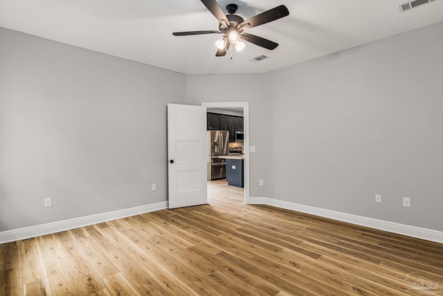 empty room with ceiling fan and light hardwood / wood-style floors