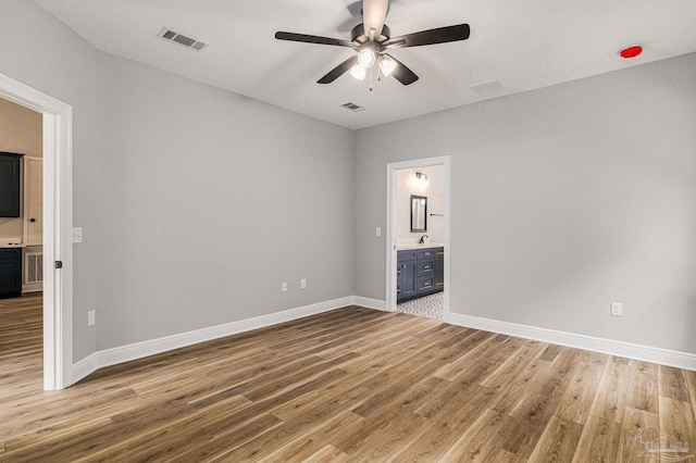 unfurnished bedroom featuring sink, ensuite bathroom, wood-type flooring, and ceiling fan