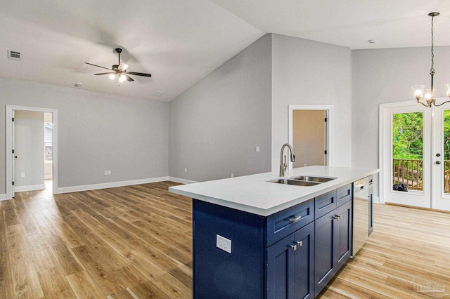 kitchen featuring light hardwood / wood-style flooring, ceiling fan with notable chandelier, sink, decorative light fixtures, and a center island with sink