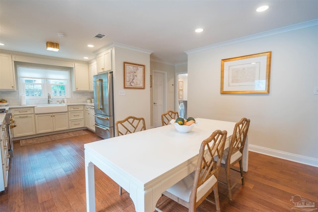 dining room featuring sink, wood-type flooring, and crown molding