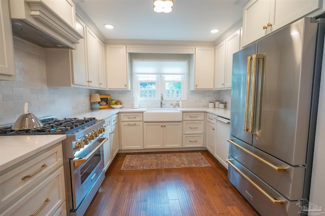 kitchen featuring tasteful backsplash, custom range hood, high end appliances, sink, and white cabinets