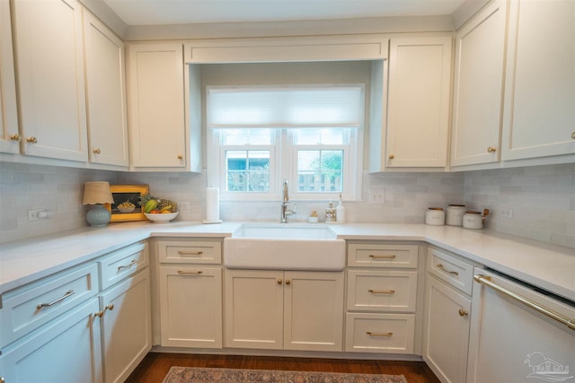 kitchen featuring white dishwasher, backsplash, white cabinets, and sink