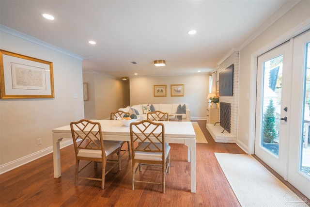 dining space with a brick fireplace, dark wood-type flooring, and ornamental molding