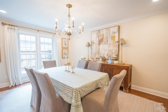 dining room with hardwood / wood-style flooring, ornamental molding, and a notable chandelier