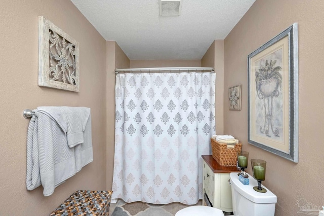 bathroom featuring a textured ceiling, walk in shower, and toilet