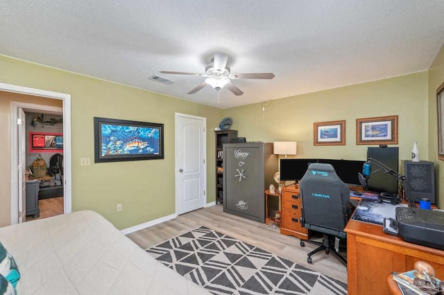 home office with ceiling fan, light hardwood / wood-style flooring, and a textured ceiling