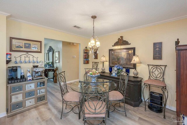 dining room featuring ornamental molding, a textured ceiling, a notable chandelier, and hardwood / wood-style flooring