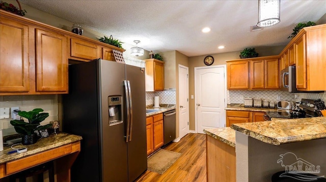 1462 Camrose Pl, Pensacola, FL 32534 - kitchen featuring stainless steel appliances, brown cabinetry, light wood-style floors, backsplash, and a peninsula