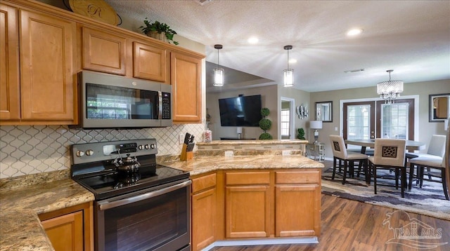 1462 Camrose Pl, Pensacola, FL 32534 - kitchen featuring stainless steel appliances, a peninsula, dark wood-style flooring, tasteful backsplash, and hanging light fixtures