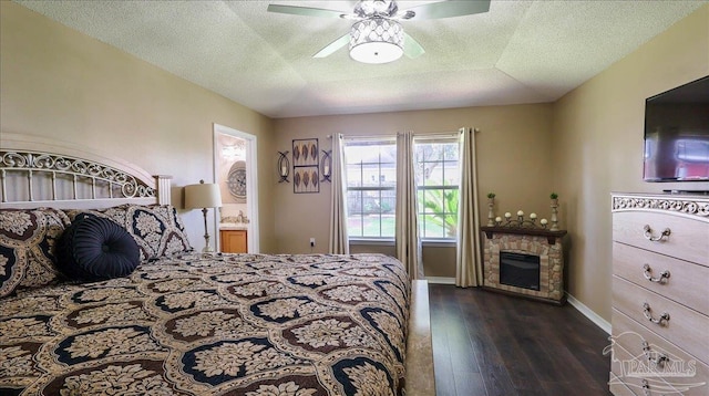 1462 Camrose Pl, Pensacola, FL 32534 - bedroom with dark wood-style floors, baseboards, a stone fireplace, a textured ceiling, and ceiling fan