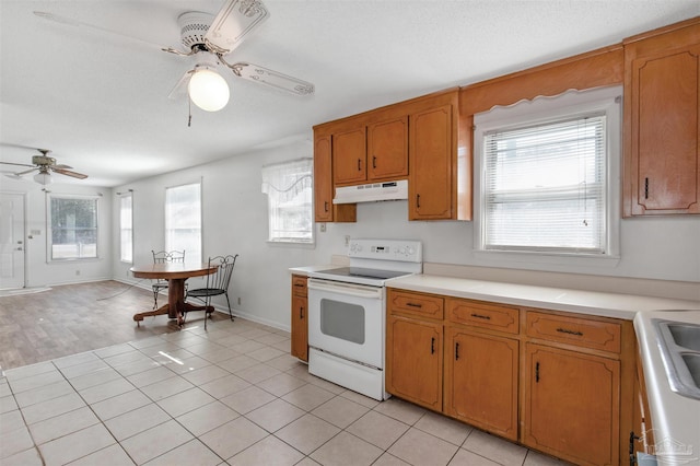 kitchen featuring a textured ceiling, ceiling fan, light tile patterned floors, and electric range