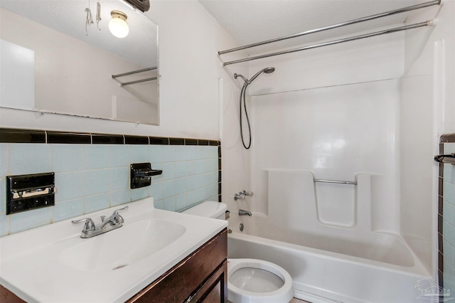 full bathroom featuring tub / shower combination, a textured ceiling, vanity, tile walls, and toilet