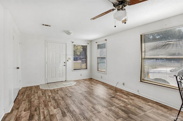 empty room with ceiling fan and light hardwood / wood-style flooring