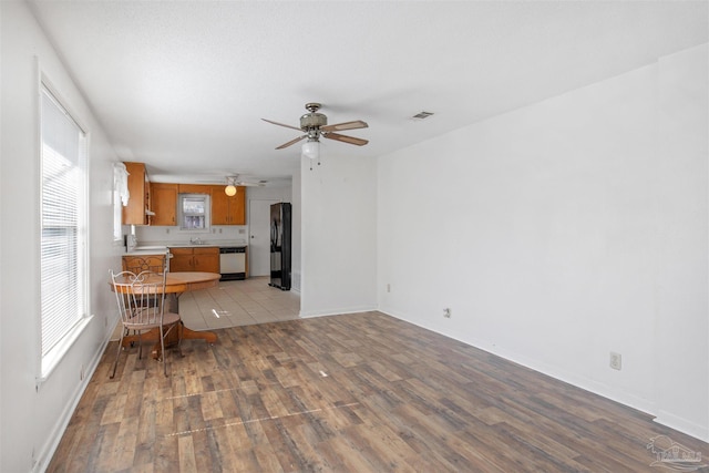 interior space featuring light wood-type flooring, black fridge, dishwasher, and sink