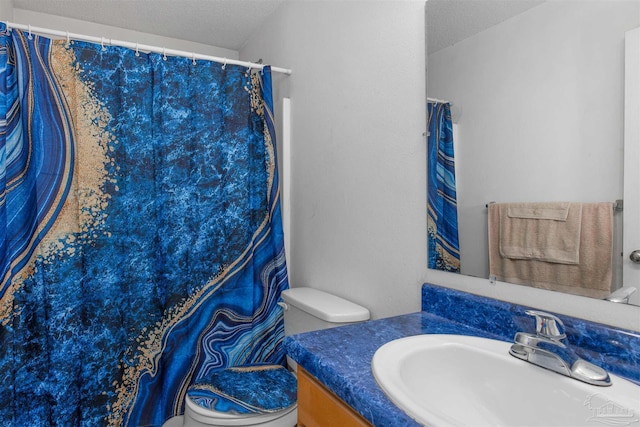 bathroom featuring toilet, vanity, and a textured ceiling