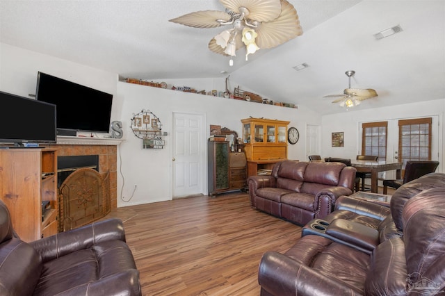 living room with lofted ceiling, french doors, a fireplace, and hardwood / wood-style floors