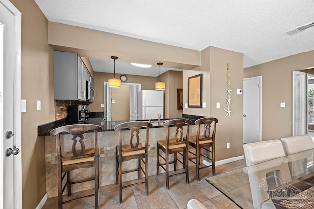 8425 Gulf Blvd Unit 206, Navarre Beach, FL 32566 - kitchen featuring stainless steel microwave, a peninsula, freestanding refrigerator, baseboards, and dark countertops