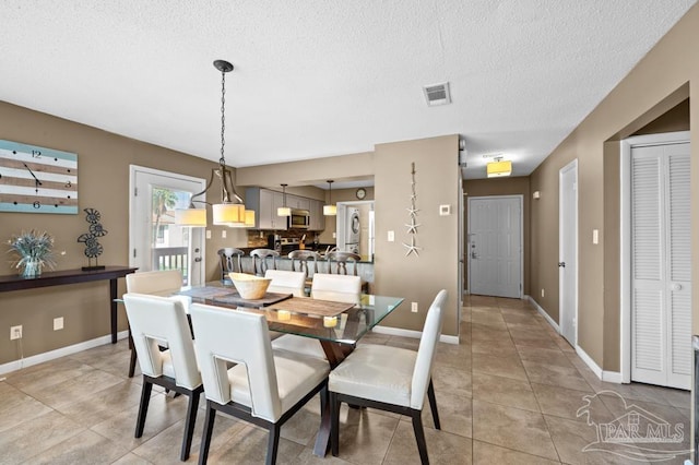 8425 Gulf Blvd Unit 206, Navarre Beach, FL 32566 - dining space with a textured ceiling, visible vents, baseboards, and light tile patterned floors